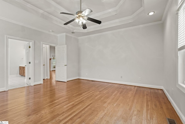 unfurnished room with light wood-type flooring, a tray ceiling, and crown molding