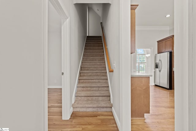 stairway with hardwood / wood-style flooring and crown molding