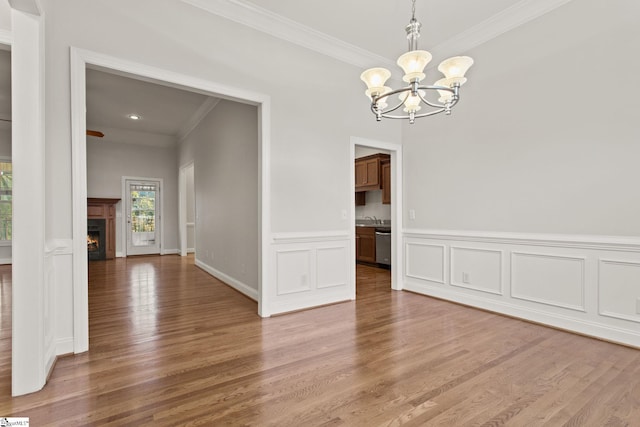 unfurnished dining area with crown molding, wood-type flooring, and a notable chandelier