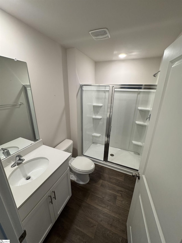 bathroom with a shower with door, vanity, wood-type flooring, and toilet