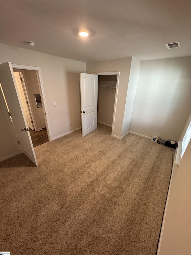 unfurnished bedroom with light carpet and a closet