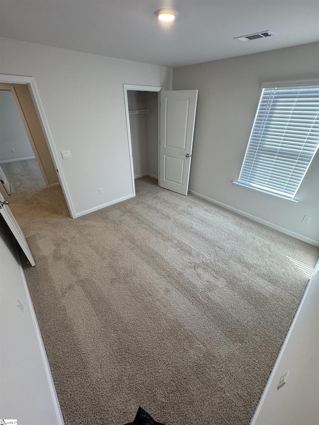 unfurnished bedroom with light carpet and a closet