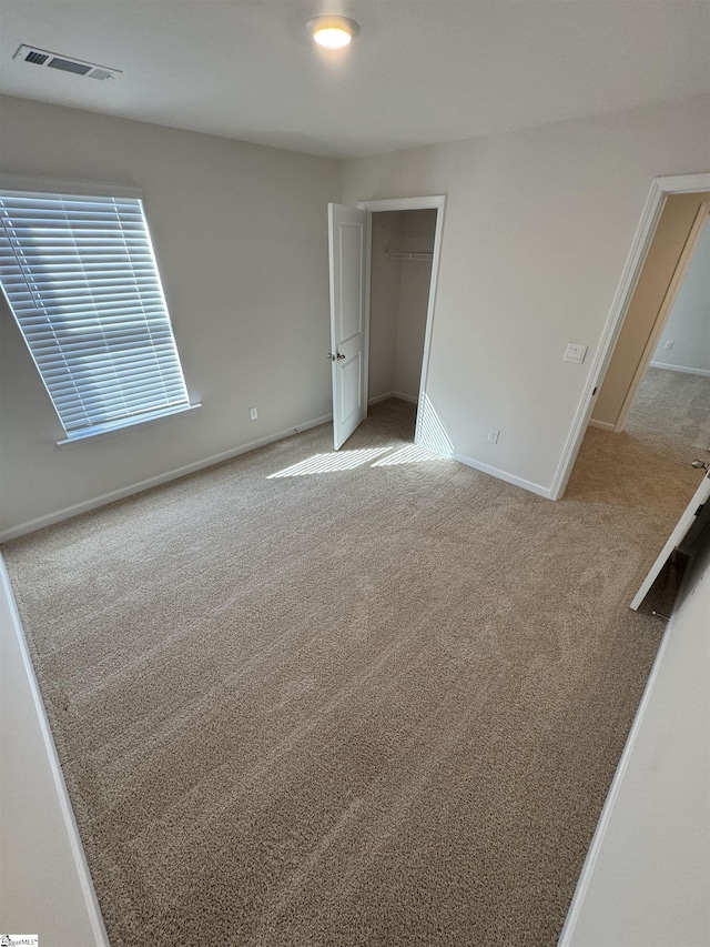 unfurnished bedroom featuring light carpet and a closet