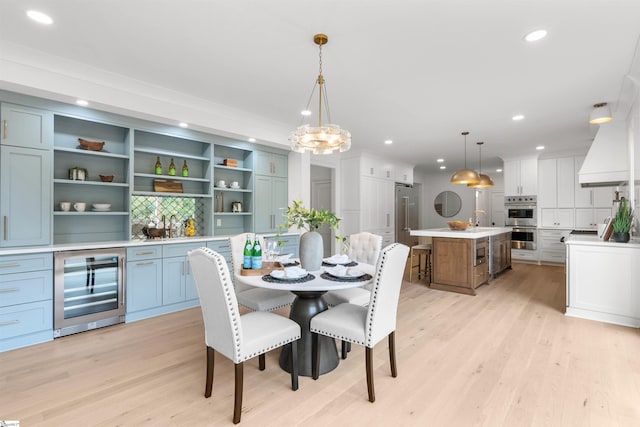 dining space with light hardwood / wood-style flooring, beverage cooler, and sink