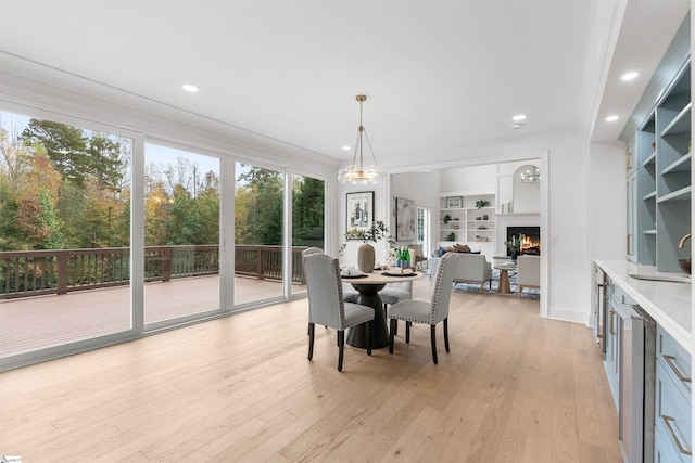 dining space featuring built in shelves, sink, a notable chandelier, and light wood-type flooring