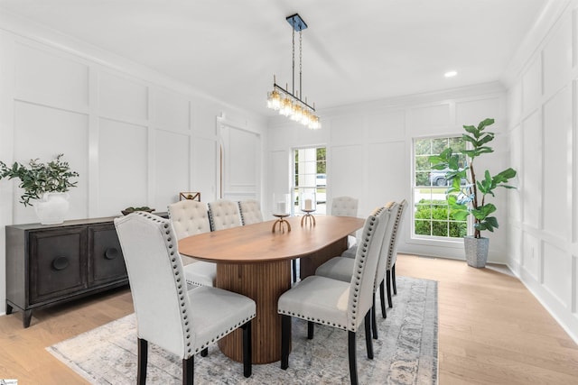 dining room with ornamental molding, light wood-type flooring, and a notable chandelier