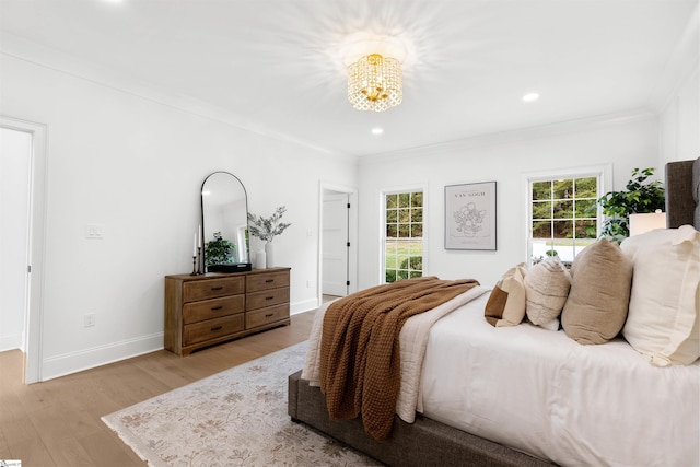 bedroom featuring an inviting chandelier, light hardwood / wood-style flooring, and ornamental molding