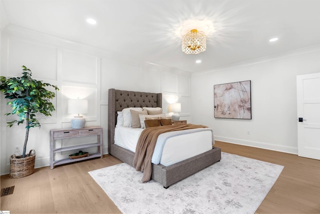 bedroom featuring hardwood / wood-style floors, an inviting chandelier, and crown molding