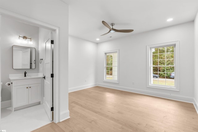 unfurnished room featuring light hardwood / wood-style floors, ceiling fan, and sink