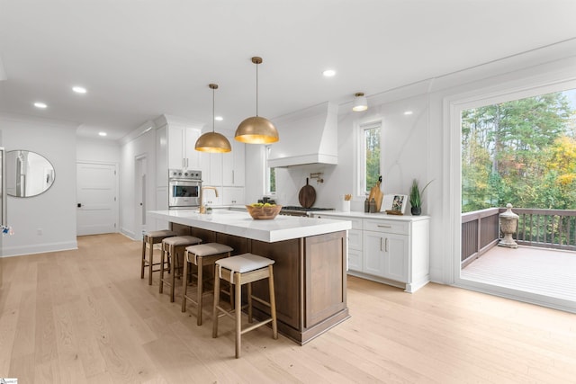 kitchen with pendant lighting, white cabinetry, light hardwood / wood-style flooring, and stainless steel appliances