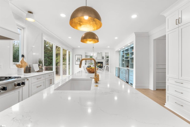 kitchen with light stone countertops, pendant lighting, white cabinetry, and sink