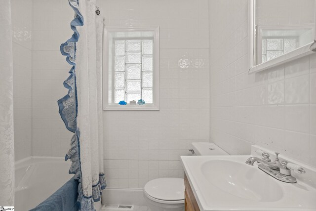 full bathroom with shower / bath combo with shower curtain, vanity, tile walls, and toilet