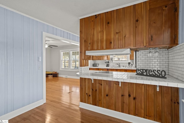 kitchen featuring tasteful backsplash, tile countertops, light hardwood / wood-style flooring, and ornamental molding