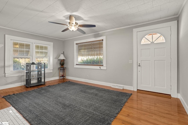 entrance foyer featuring ceiling fan, wood-type flooring, and crown molding