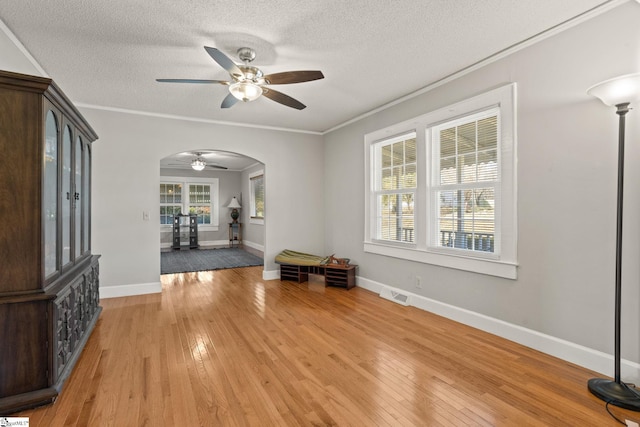 entryway with ceiling fan, ornamental molding, a textured ceiling, and light wood-type flooring