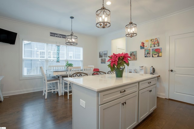 kitchen with dark wood-type flooring, a kitchen island, hanging light fixtures, and ornamental molding