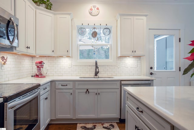 kitchen featuring backsplash, dark wood-type flooring, white cabinets, sink, and appliances with stainless steel finishes