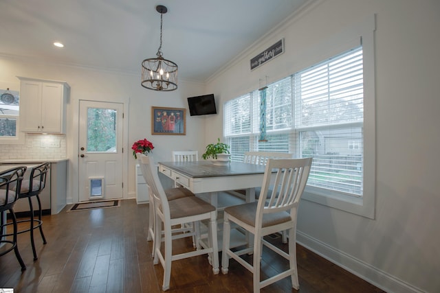 dining space with dark hardwood / wood-style floors, crown molding, and a chandelier