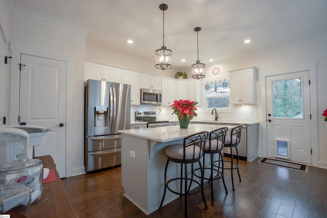 kitchen featuring white cabinetry, a center island, dark hardwood / wood-style floors, pendant lighting, and appliances with stainless steel finishes