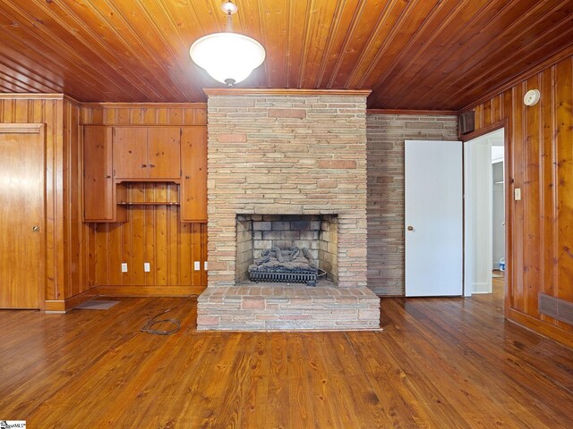 unfurnished living room with wood walls, wood-type flooring, and wooden ceiling