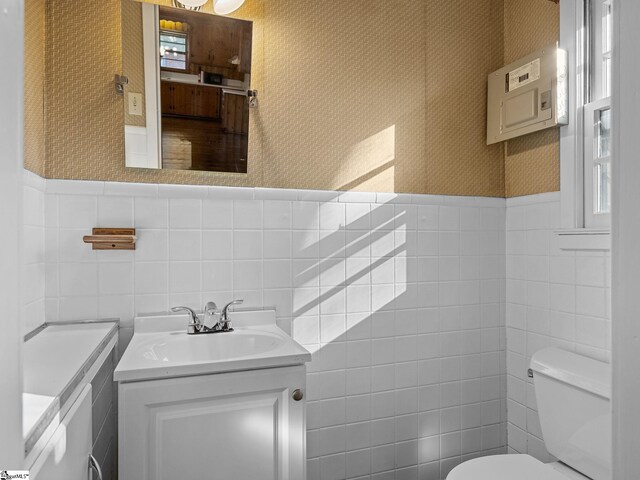 bathroom with vanity, toilet, and tile walls