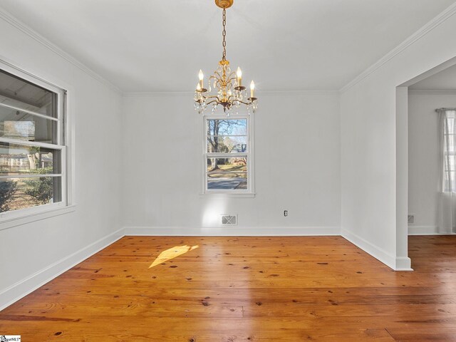 unfurnished dining area featuring a chandelier, crown molding, a healthy amount of sunlight, and wood-type flooring