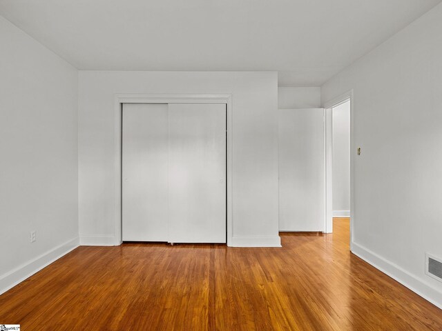 unfurnished bedroom with hardwood / wood-style flooring and a closet