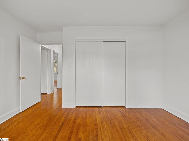 unfurnished bedroom featuring a closet and hardwood / wood-style floors