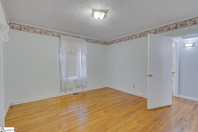 spare room featuring crown molding, hardwood / wood-style floors, and a textured ceiling