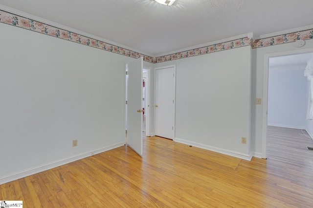 spare room featuring light hardwood / wood-style floors and a textured ceiling