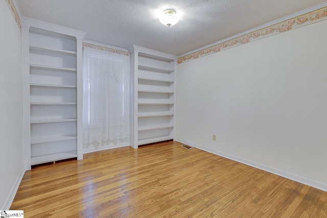 unfurnished bedroom featuring light wood-type flooring, a textured ceiling, and ornamental molding