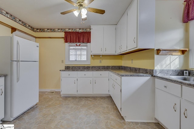 kitchen featuring white cabinets, white fridge, ceiling fan, and sink