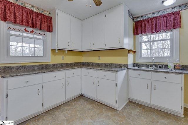 kitchen with white cabinets, ceiling fan, and sink