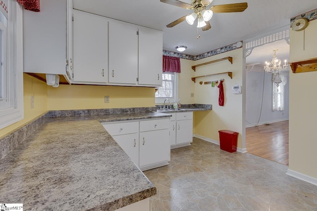 kitchen with ceiling fan with notable chandelier, sink, light hardwood / wood-style flooring, white cabinets, and hanging light fixtures