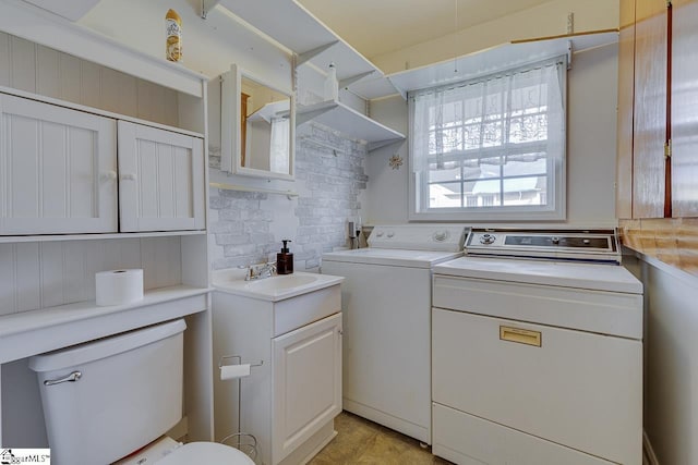 clothes washing area with independent washer and dryer and sink