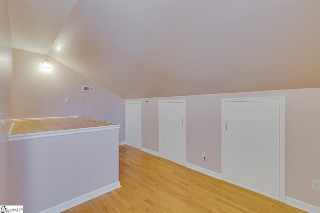 bonus room with light wood-type flooring and lofted ceiling