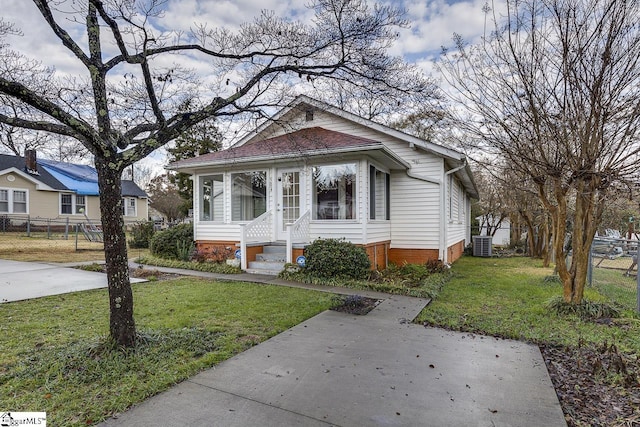 bungalow-style home with central AC unit and a front lawn