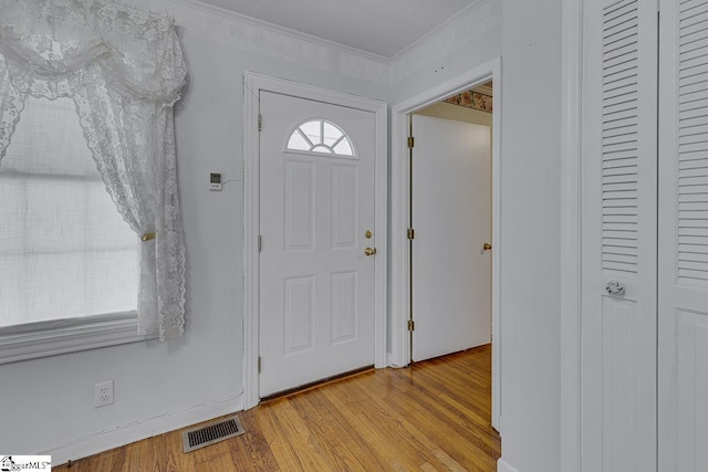 entrance foyer with light hardwood / wood-style flooring and crown molding