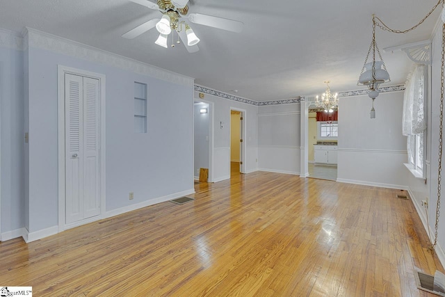 interior space with ceiling fan with notable chandelier, ornamental molding, and light hardwood / wood-style flooring