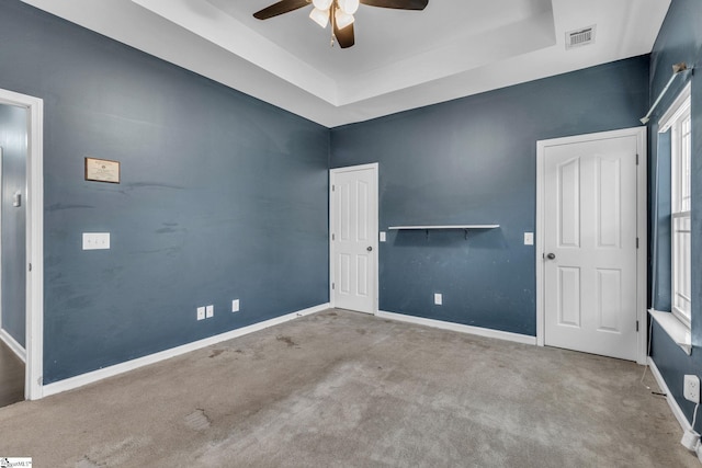 empty room featuring a tray ceiling, plenty of natural light, and carpet floors