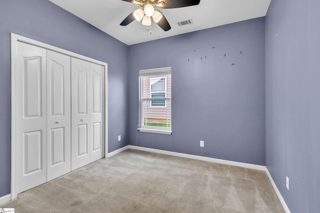 unfurnished bedroom with a closet, light colored carpet, and ceiling fan