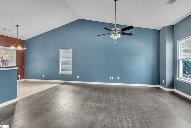 unfurnished living room featuring ceiling fan with notable chandelier, dark wood-type flooring, and vaulted ceiling