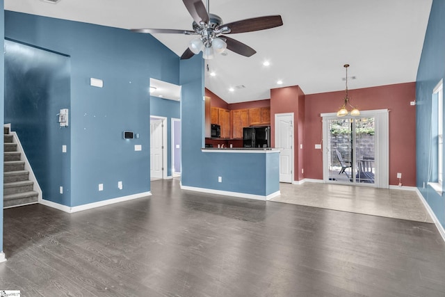 unfurnished living room with high vaulted ceiling, dark wood-type flooring, and ceiling fan with notable chandelier