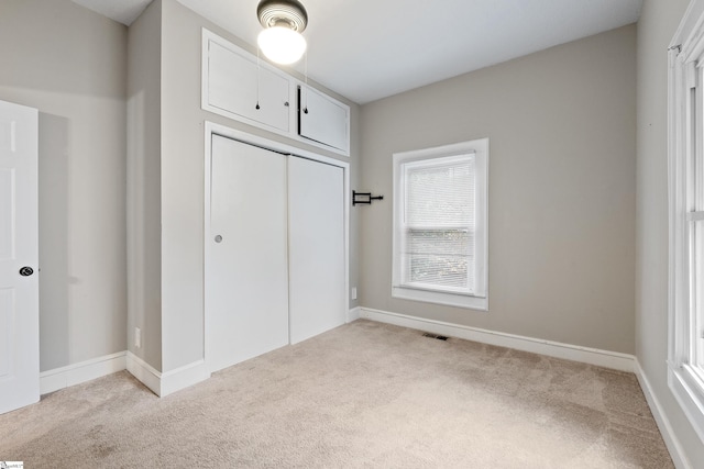 unfurnished bedroom with light carpet and a closet
