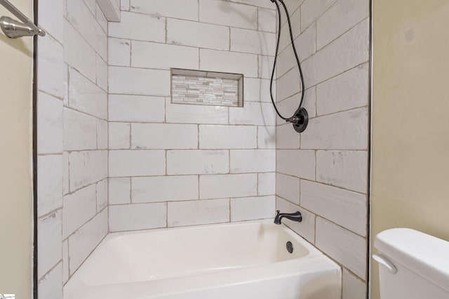 bathroom with toilet and tiled shower / bath
