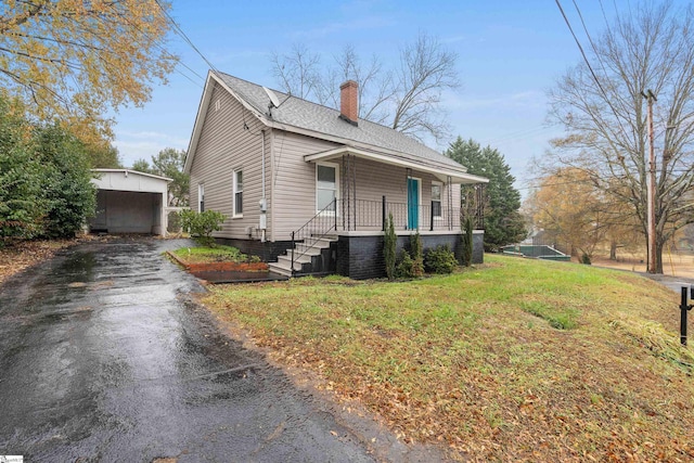 view of side of property featuring a lawn, covered porch, an outdoor structure, and a garage