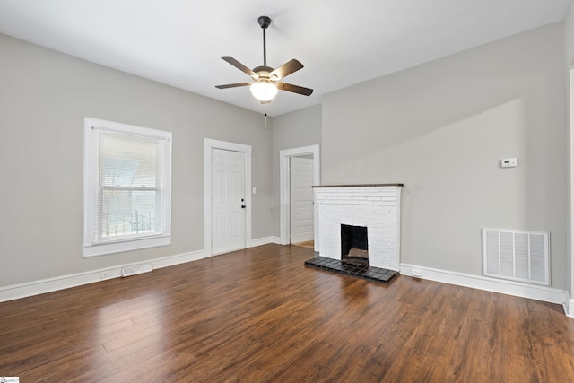 unfurnished living room featuring dark hardwood / wood-style floors, a brick fireplace, and ceiling fan