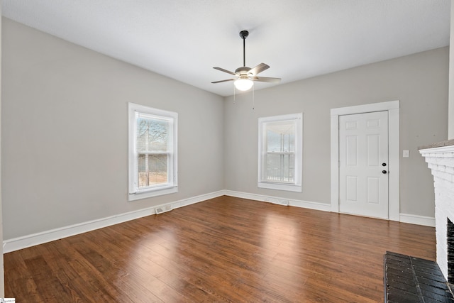 interior space with hardwood / wood-style floors, ceiling fan, a healthy amount of sunlight, and a brick fireplace