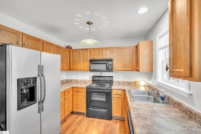 kitchen featuring sink, black appliances, decorative light fixtures, and light hardwood / wood-style flooring