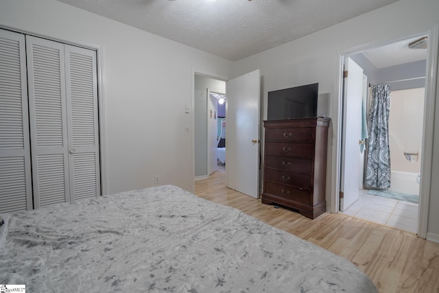 bedroom featuring a textured ceiling, ensuite bathroom, light hardwood / wood-style flooring, and a closet